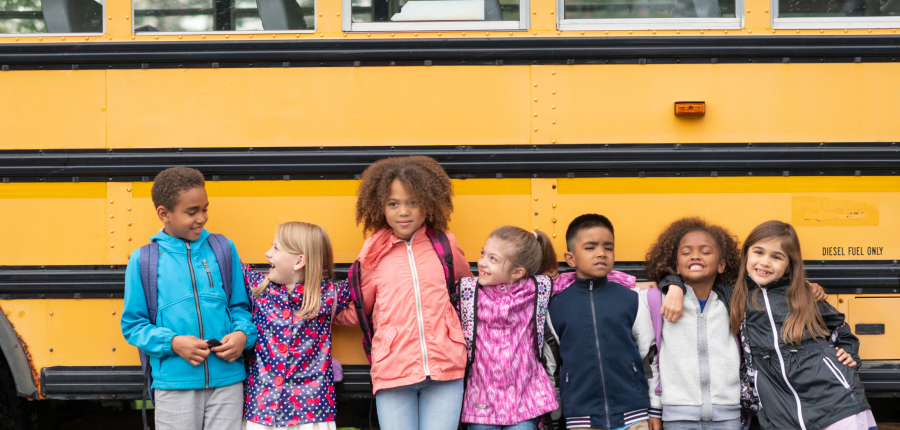 group of school age children in front of a bus